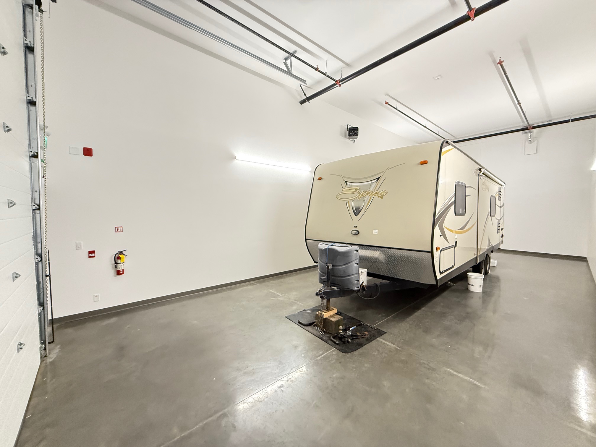 A Travel-trailer being stored in an indoor storage unit in Hope, BC. The walls have lighting and drywall, and the floor is made of concrete.